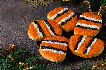Tiger Sandwiches for New Year 2022 of carrot, eggs and black olives on white bread on plate on brown background