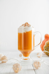 Cup with foam and cinnamon on background of pumpkins. Pumpkin autumn warming drink close-up and copy space...