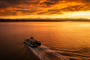 Ferry Boat Servicing a Small Island Near Bellingham, Washington. This vessel runs between Lummi Island and the mainland. Aerial drone view captures a spectacular sunrise and cloudscape and Mt. Baker. 