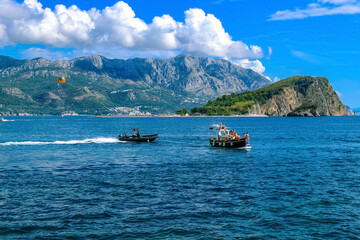 Yachts, boats and parachute in the bay of the city of Budva, Montenegro, the Balkans, the Adriatic Sea. Mountains and clouds.