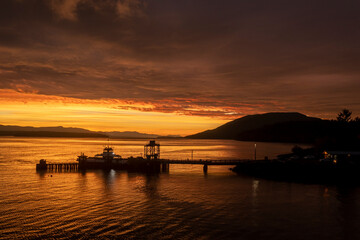 Fototapeta na wymiar Ferry Boat Servicing a Small Island Near Bellingham, Washington. Aerial drone view captures a spectacular sunrise and cloudscape. 