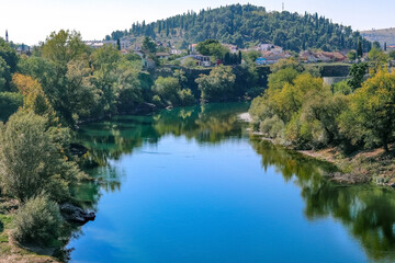 The capital of Montenegro Podgorica and a view of the Moraca river. Autumn nature, mountains, houses, cityscape.