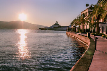 A huge luxury yacht on the embankment of Tivat, Montenegro, the Balkans, the Bay of Kotor, the Adriatic Sea. Houses, mountains, palms and sunset.
