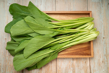Fresh Chinese cabbage or Choi Sum, Chinese Flowering Cabbage  in a wooden tray ready to cook.