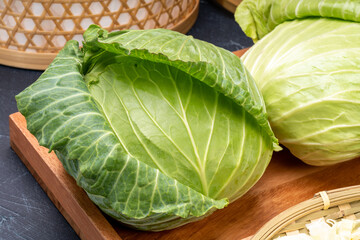 Fresh cabbage and slice cabbage with woven bamboo baskets on wooden background. 