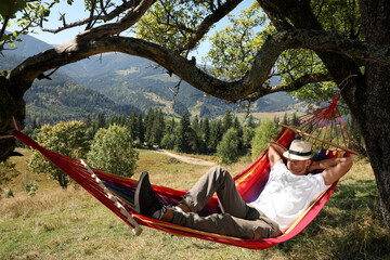 Fototapeta na wymiar Man resting in hammock outdoors on sunny day