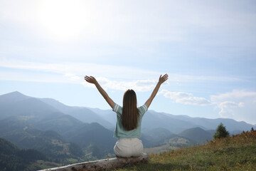 Young woman in peaceful mountains, back view. Feeling freedom