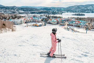 Obraz premium Skiing woman. Alpine ski - skier looking mountain village ski resort view starting skiing downhill on snow covered ski trail slope in winter. Mont Tremblant, Quebec, Canada