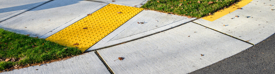 Closeup of disabled sidewalk entry on a cold sunny day, yellow markings
