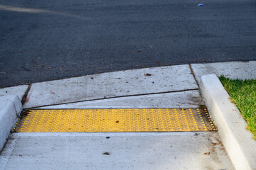 Closeup of disabled sidewalk entry on a cold sunny day, yellow markings
