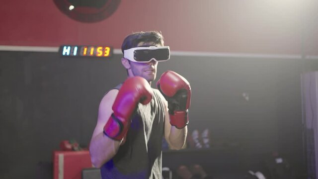 smart caucasian man wearing red boxing gloves and using glasses of virtual reality in sport gym.Smartphone using with VR headset,future technology concept.Man using VR glasses in colorful neon lights.