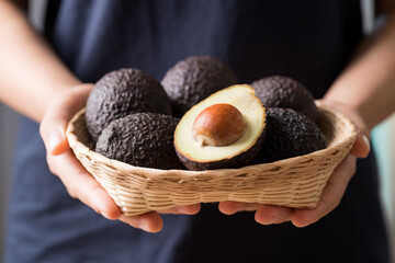 Ripe hass avocado fruit in a basket holding by woman hand, Healthy eating