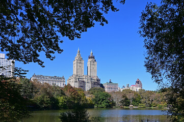 Fototapeta na wymiar Central Park in New York with autumn foliage and skyscrapers in background on clear cloudless day.