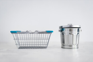 consumerism vs sustainable intentional shopping, shopping basket for good to be purchased next to recycling bin for excess goods being produced or bought