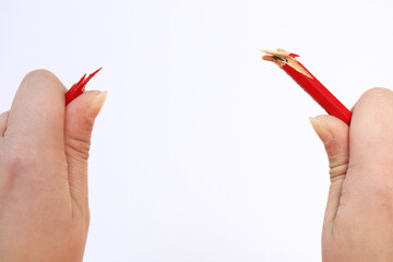 two hands holding a red pencil that has just snapped under the pressure. Concept of stress, anger management, pressure in the work place, parenting and breakdown. split up.