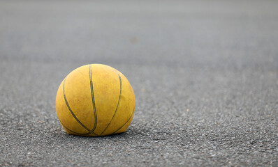 Left hand focus, old tired deflated let down yellow basketball on a road surafce concept. needs...