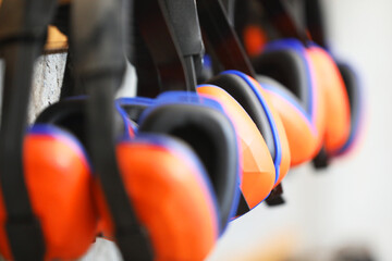 row of orange ear muffs ear protection on a rack. workplace health and safety deafness concept....