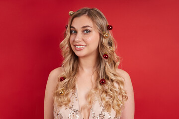 beautiful lady in a smart dress, with Christmas balls in her hair, a portrait on a red background. Merry christmas, happy new year