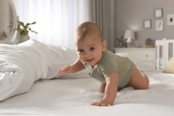 Cute baby crawling on bed at home