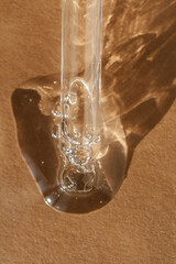 The texture of serum or oil with a pipette on a beige background.