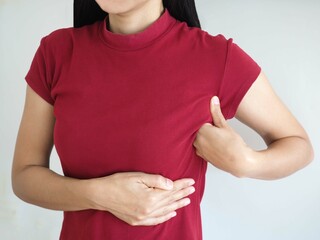Woman wearing red t-shirt checking her breast, breast self-exam (BSE).  closeup photo, blurred.