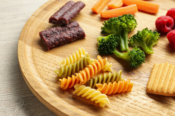 Wooden board with different finger foods for baby on table, closeup
