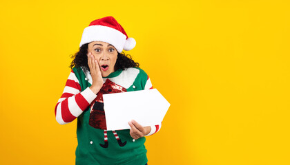 Portrait of Latin adult woman smiling and pointing up to blank board with copy space on a yellow background in Mexico latin america