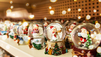 A Christmas glass ball with a snowman stands among other glass balls on a store shelf. Selective focus. Defocus lights.
Traditional symbolic small gift for Christmas. Christmas ball. Good New Year spi