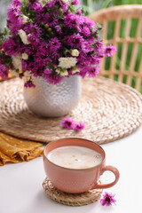 Cup of aromatic coffee and beautiful flowers on white table
