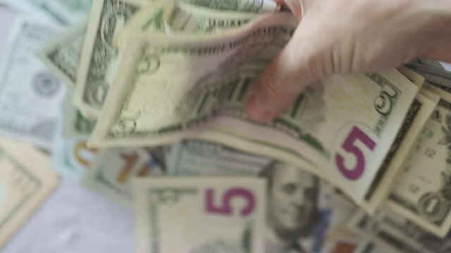 hands shoveling money taking messing crumpling dollar bills shaking it