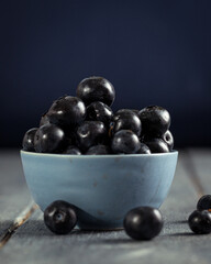 Blue bowl of blueberries on a blue wooden surface.