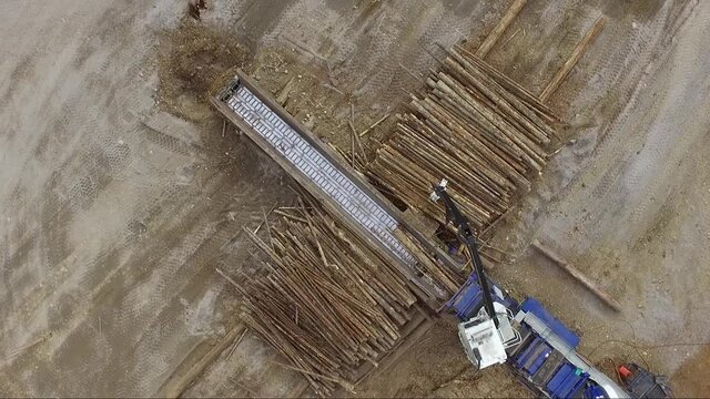 Overhead drone view of machine adding logs into an industrial wood chipper creating wood chips for pulp and then paper.