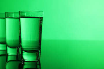 Vodka on table against green background, space for text