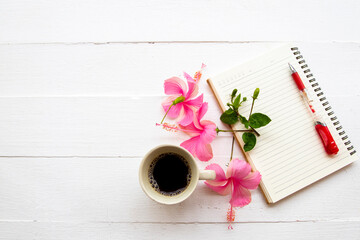 notebook planner, hot coffee espresso and flowers hibiscus arrangement flat lay postcard style on background wooden white