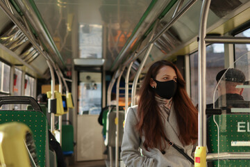 Fototapeta na wymiar European woman passenger wearing a face mask when traveling by bus