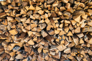 Logs of firewood piled under canopy, closeup.