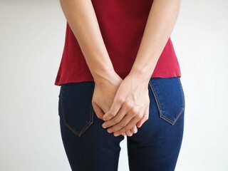Young woman has anal cancer and touching her butt on white background. closeup photo, blurred.