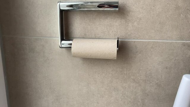 Hand grabbing last piece of toilet paper in the bathroom.
Having Problems with empty toilet paper.
 