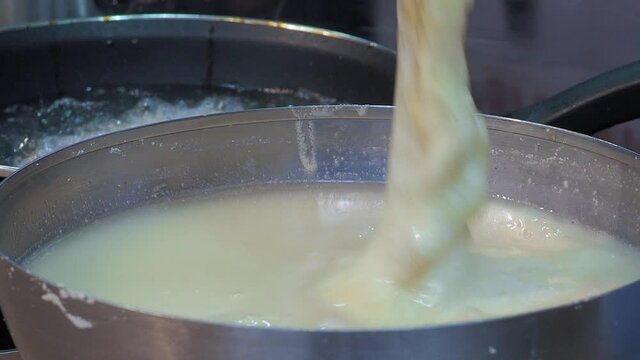Cook batters fish pieces in water with flour and then fries them