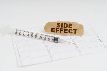 On the table is a cardiogram, a syringe and paper with the inscription - SIDE EFFECT