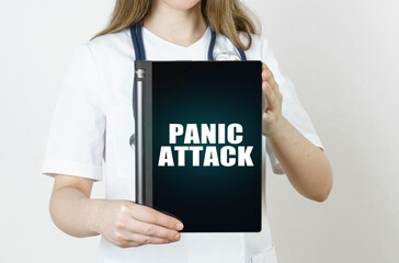 Fototapeta na wymiar The doctor is holding a tablet with the inscription - PANIC ATTACK