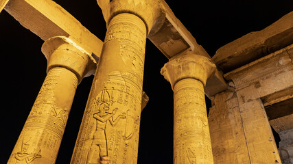 Colonnade in the ancient temple of Kom Ombo. The dilapidated columns are illuminated against the...