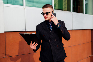 A young man is walking down the street and talking on the phone. An entrepreneur goes to work in the office.