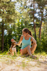 Naklejka na ściany i meble a beautiful and athletic European girl does sports in nature with her dog. fitness and yoga and meditation in the fresh air. jogging and warm-up for health and beauty, a woman and a dog do athletics