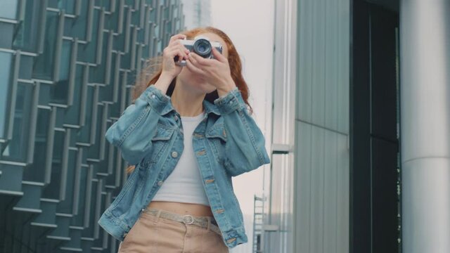Young woman in city taking photo on digital camera to post to social media - shot in slow motion