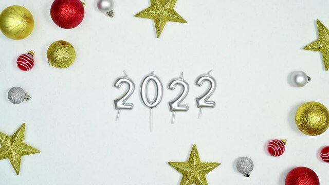 2022 number for New year and Christmas golf and red ornaments and glitter stars appear on white theme. Stop motion 