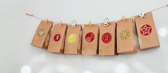 Hanging Christmas advent calendar on wall. Handmade craft bags with gifts and tasks for children. Countdown for Christmas eve, waiting for miracle. Eco, diy festive decoration with dates, banner