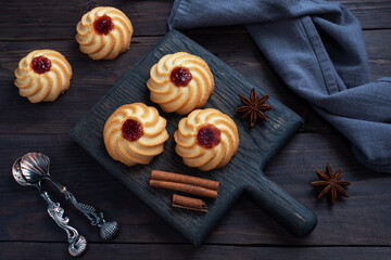 Kurabye shortbread cookies with berry jam in a black plate. Delicious dessert, dark wooden background with copy space.