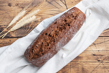 Rye bread with cereals, a fresh loaf of grain baguette on a wooden background.