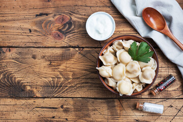 Traditional pelmeni, ravioli, dumplings filled with meat on plate, russian kitchen. Wooden rustic background, copy space.